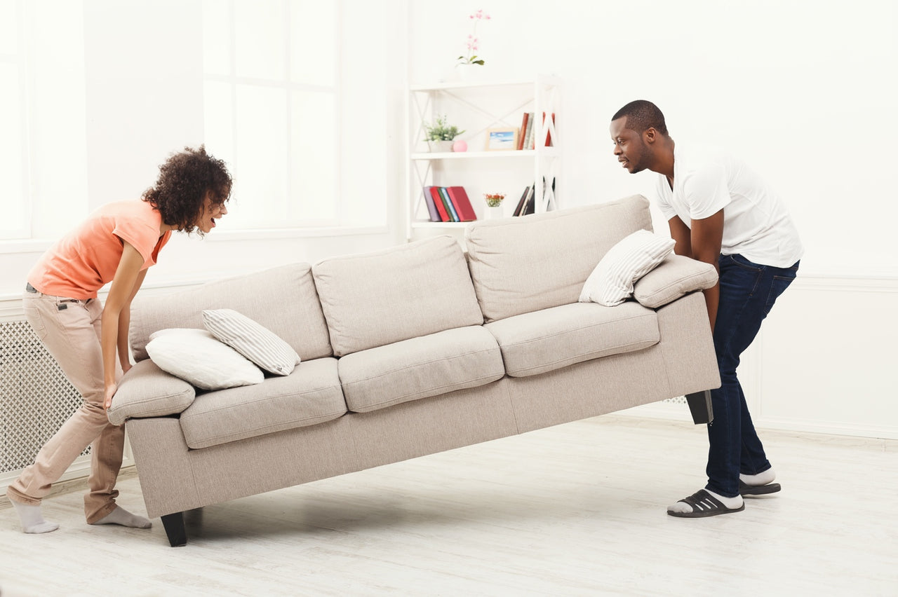 couple struggling to move heavy household furniture